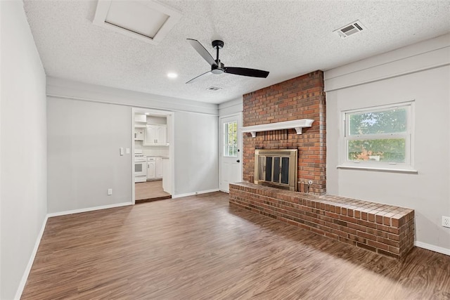 unfurnished living room featuring wood-type flooring, a textured ceiling, a wealth of natural light, and ceiling fan