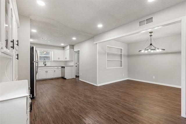 kitchen featuring white cabinets, dark hardwood / wood-style floors, a textured ceiling, and stainless steel refrigerator