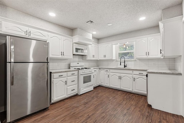 kitchen featuring white appliances, white cabinets, sink, dark hardwood / wood-style floors, and a textured ceiling