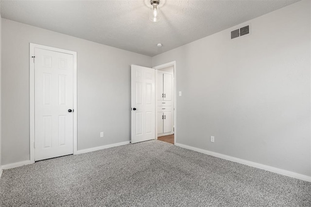 carpeted empty room featuring a textured ceiling