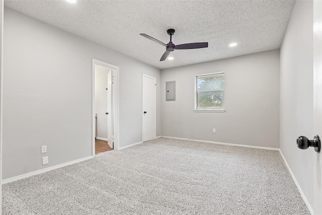 empty room featuring ceiling fan, carpet floors, a textured ceiling, and electric panel