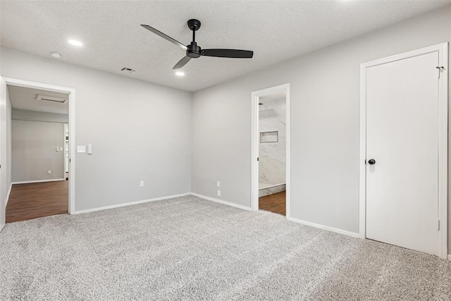 unfurnished bedroom featuring connected bathroom, ceiling fan, dark carpet, and a textured ceiling