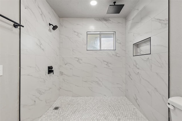 bathroom with a tile shower and toilet