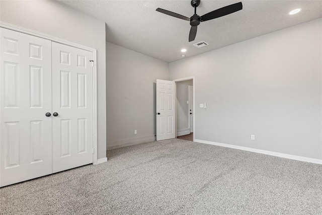 unfurnished bedroom featuring carpet, a textured ceiling, a closet, and ceiling fan