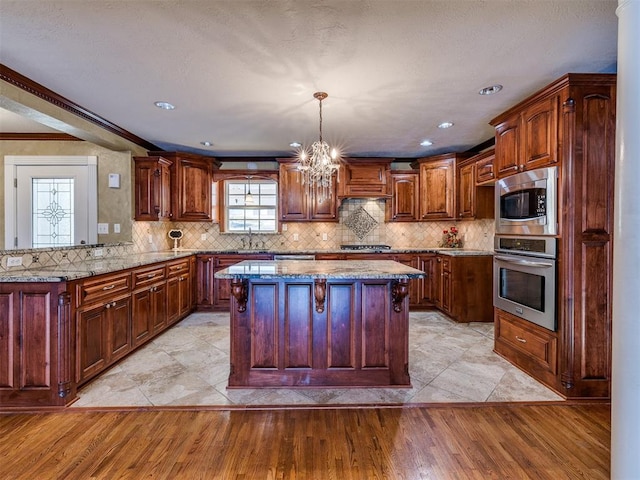 kitchen featuring appliances with stainless steel finishes, light wood-type flooring, ornamental molding, and pendant lighting