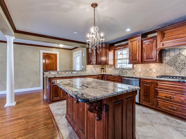 kitchen with a center island, stainless steel appliances, decorative columns, and crown molding