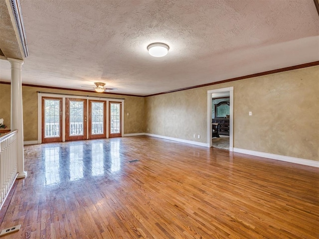 unfurnished living room with ceiling fan, ornamental molding, a textured ceiling, and light hardwood / wood-style flooring