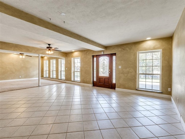 entryway featuring beamed ceiling, light tile patterned floors, a textured ceiling, and ceiling fan