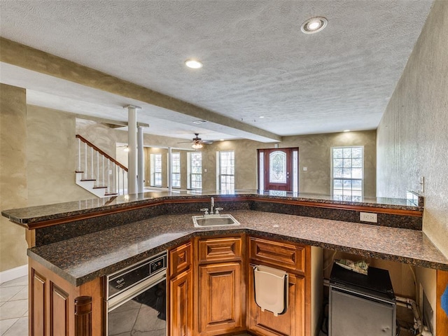 kitchen featuring kitchen peninsula, a textured ceiling, ceiling fan, sink, and light tile patterned flooring