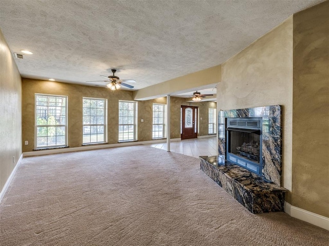 unfurnished living room featuring light carpet, a fireplace, ceiling fan, and a textured ceiling