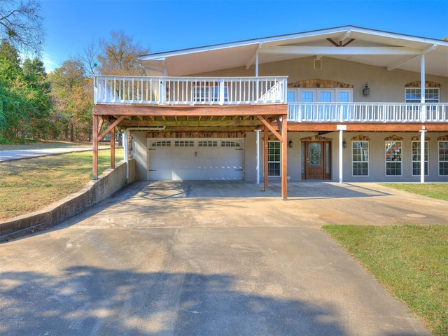 view of front of property featuring a garage, a front lawn, and a deck