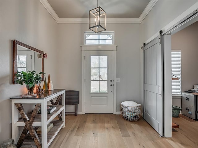 foyer featuring light wood-type flooring, a barn door, and crown molding