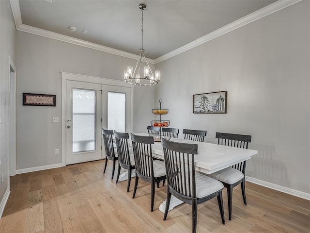 dining space featuring light wood-type flooring, crown molding, and an inviting chandelier