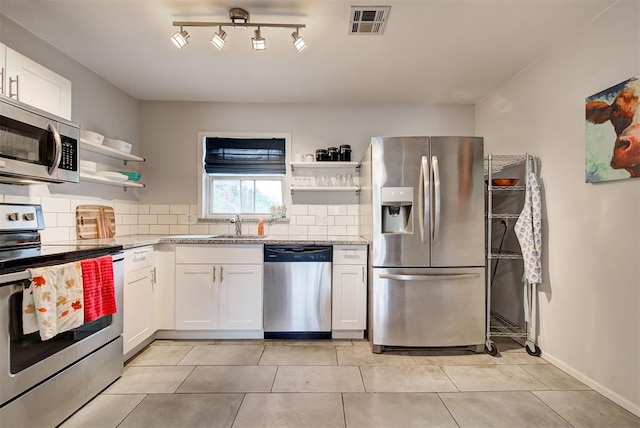 kitchen featuring white cabinets, backsplash, stainless steel appliances, and light stone counters