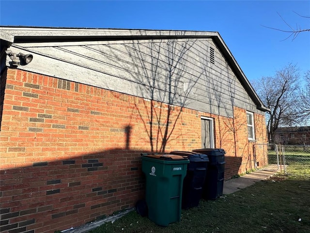 view of side of home with brick siding and fence