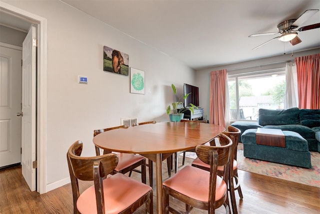 dining room featuring visible vents, baseboards, wood finished floors, and a ceiling fan