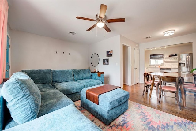 living room with wood finished floors, visible vents, and ceiling fan