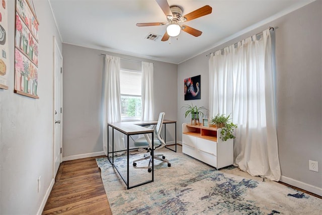 office space with visible vents, a ceiling fan, baseboards, and wood finished floors