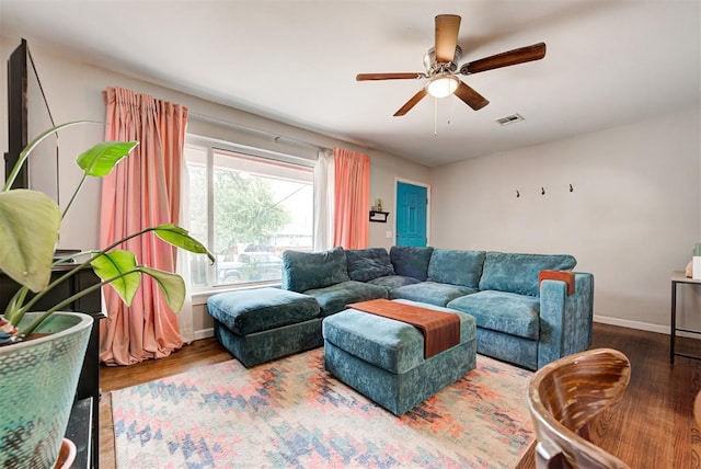 living room with ceiling fan, visible vents, baseboards, and wood finished floors