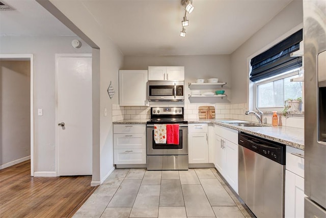 kitchen with light stone counters, visible vents, a sink, decorative backsplash, and appliances with stainless steel finishes