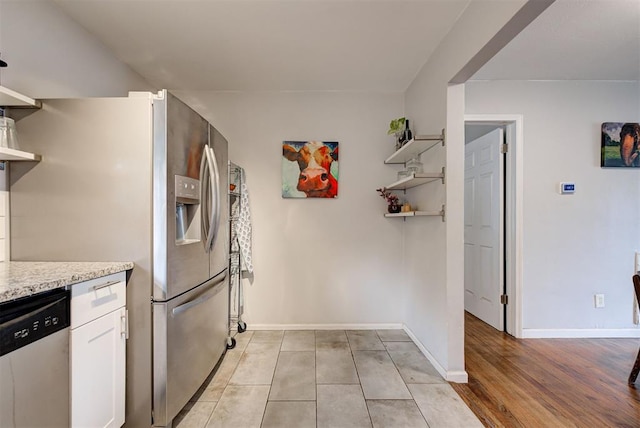 kitchen with baseboards, light stone counters, stainless steel dishwasher, white cabinetry, and open shelves