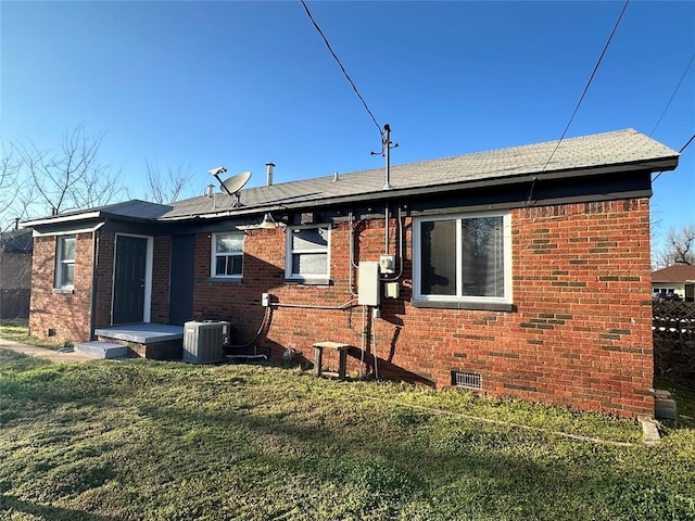 rear view of property featuring a yard, brick siding, central AC, and crawl space