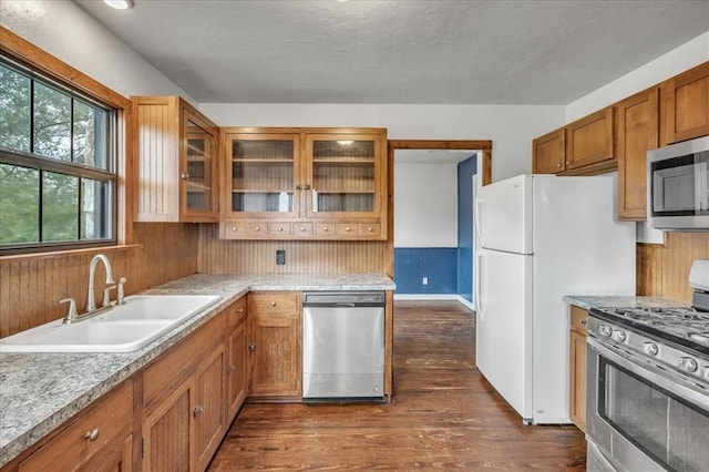 kitchen featuring dark hardwood / wood-style floors, sink, stainless steel appliances, and wooden walls