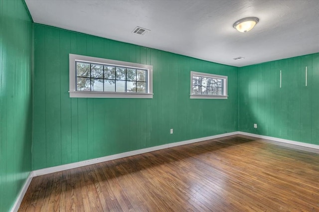 spare room with hardwood / wood-style floors and wood walls