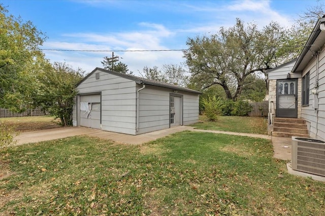 view of outbuilding featuring cooling unit, a garage, and a yard