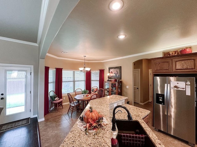 kitchen featuring light stone countertops, stainless steel refrigerator with ice dispenser, decorative light fixtures, hardwood / wood-style flooring, and ornamental molding