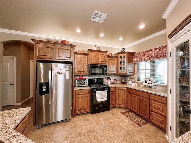 kitchen featuring decorative backsplash, light stone counters, crown molding, black appliances, and light tile patterned flooring