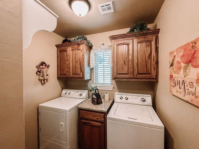 clothes washing area with cabinets and washing machine and clothes dryer