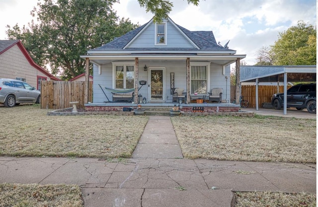 bungalow-style house with a shingled roof, covered porch, a front yard, fence, and a carport