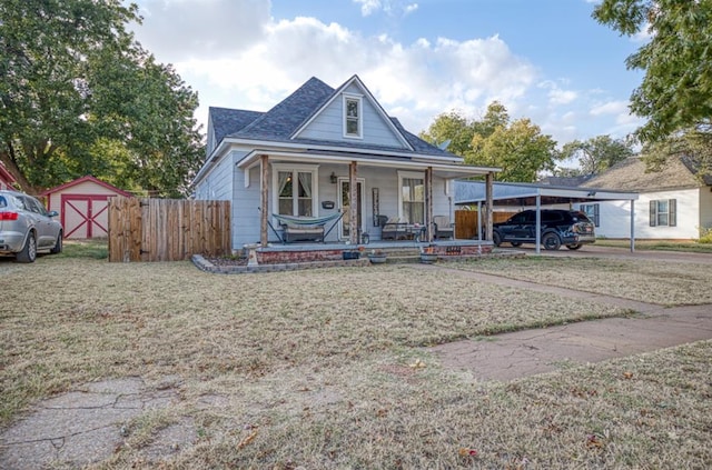 bungalow-style house featuring an outbuilding, covered porch, fence, a front lawn, and a carport