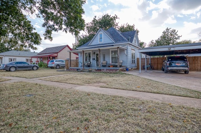 bungalow with a carport, a porch, a front lawn, and fence