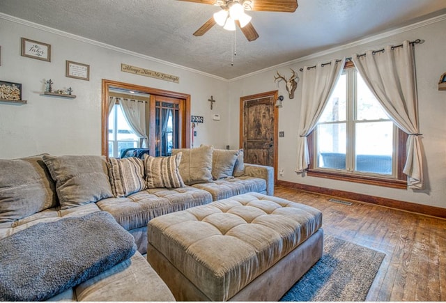 living room with a textured ceiling, hardwood / wood-style flooring, ceiling fan, and ornamental molding