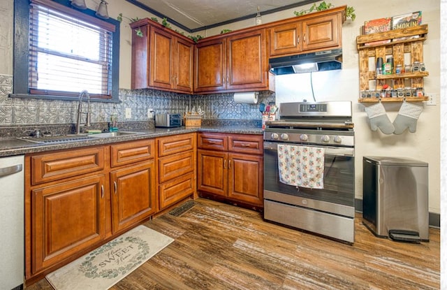 kitchen with appliances with stainless steel finishes, dark hardwood / wood-style flooring, backsplash, and sink