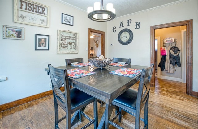 dining area featuring hardwood / wood-style floors, an inviting chandelier, and ornamental molding