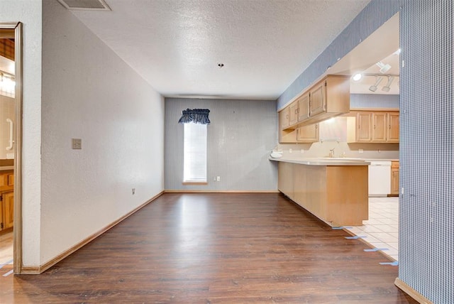 kitchen featuring white dishwasher, light brown cabinets, kitchen peninsula, and hardwood / wood-style floors