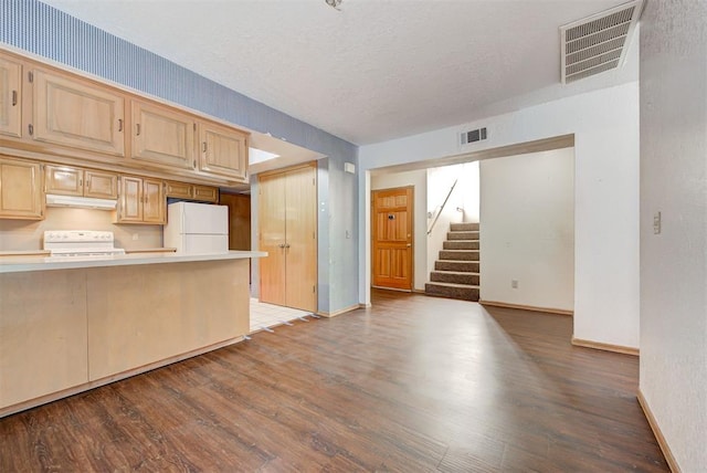 kitchen with hardwood / wood-style floors, light brown cabinets, white appliances, and a textured ceiling