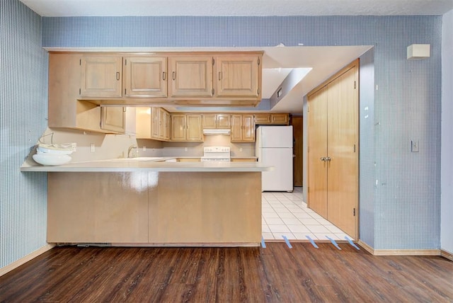 kitchen featuring light hardwood / wood-style flooring, white refrigerator, kitchen peninsula, light brown cabinetry, and range