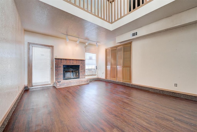 unfurnished living room featuring a fireplace, dark hardwood / wood-style flooring, and rail lighting