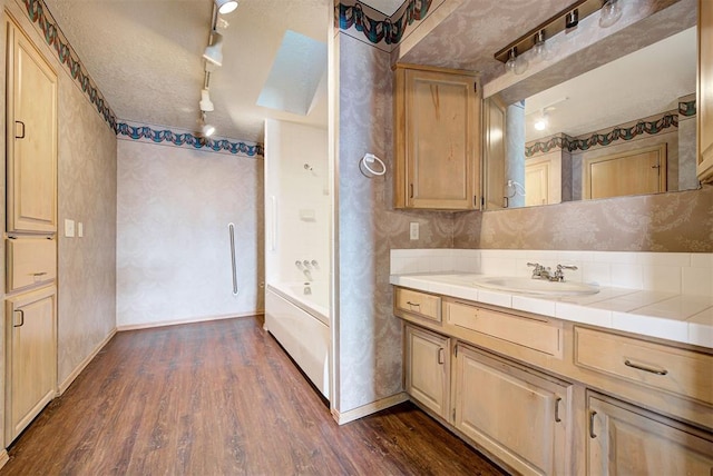 bathroom featuring track lighting, shower / bathtub combination, vanity, a textured ceiling, and wood-type flooring