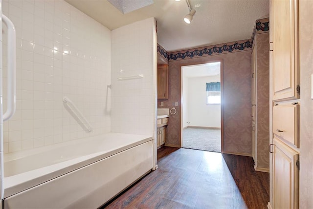 bathroom with hardwood / wood-style flooring, a textured ceiling, and bathing tub / shower combination