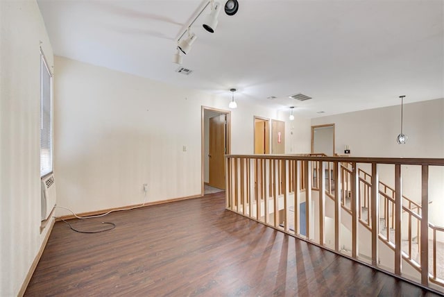 empty room with dark hardwood / wood-style flooring and rail lighting