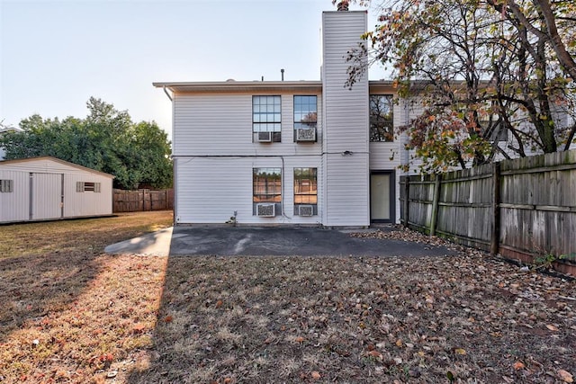 rear view of property with a storage unit, cooling unit, and a patio area