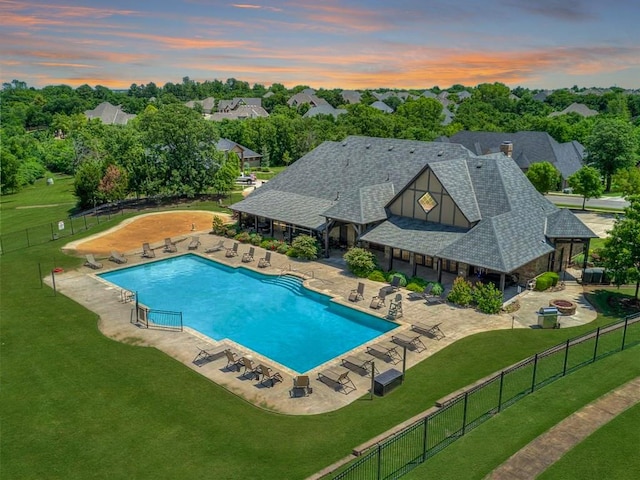 pool at dusk featuring a lawn and a patio area