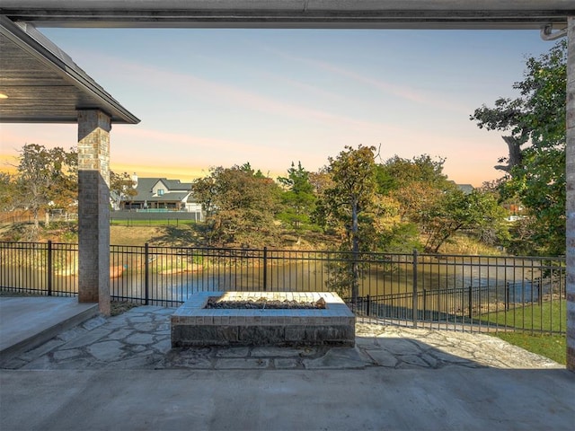 patio terrace at dusk with a water view and a fire pit