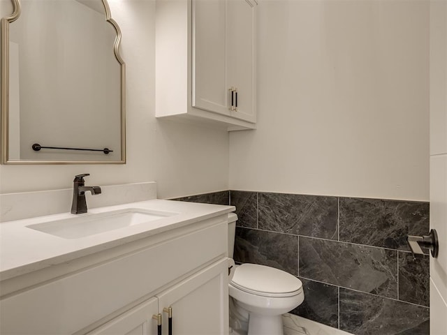 bathroom featuring tile walls, vanity, and toilet