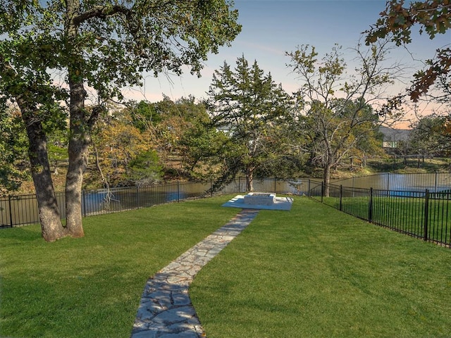 yard at dusk featuring a water view